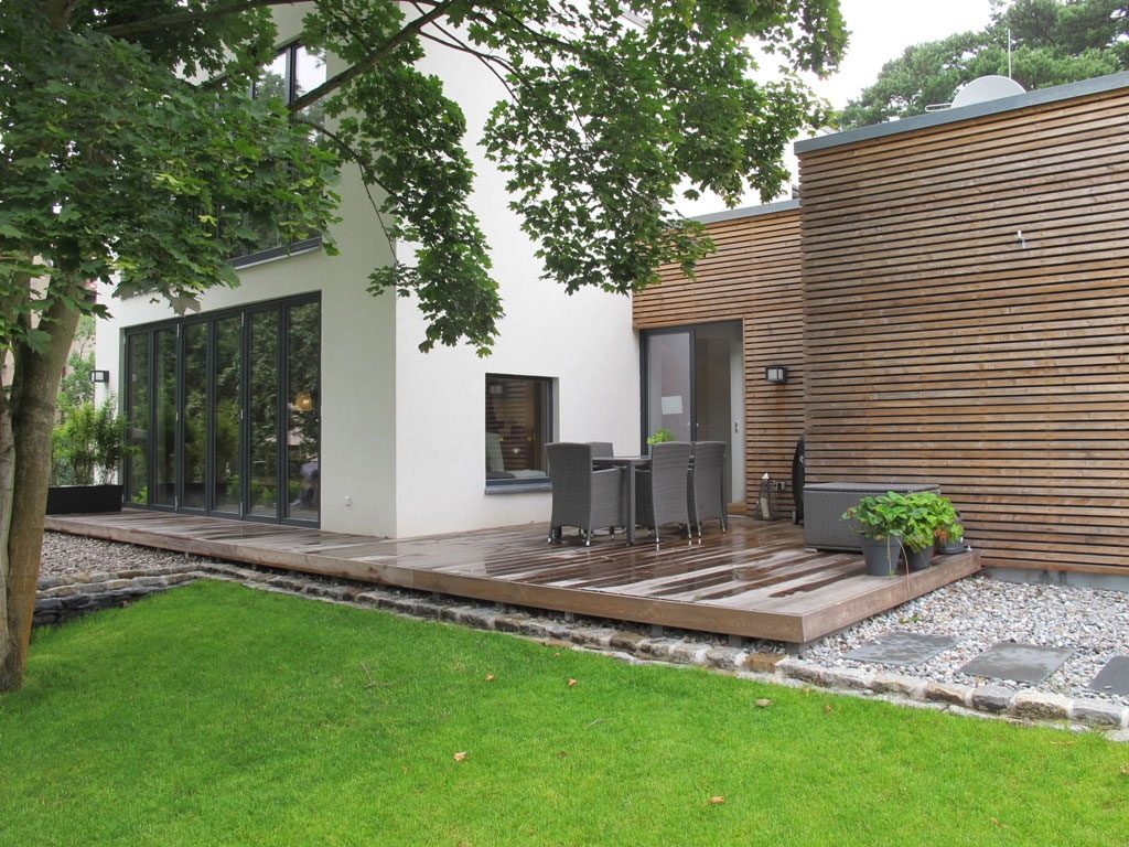 Einfamilienhaus in Birkenwerder: weißer Putzbau mit Holzdeck und Nebengebäude mit Holzlattenfassade