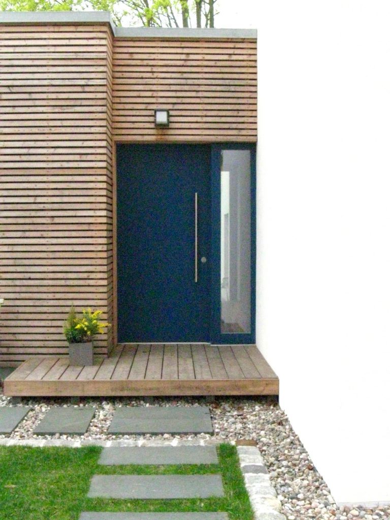 Eingang mit dunkelblauer Haustür in der Holzlattenfassade